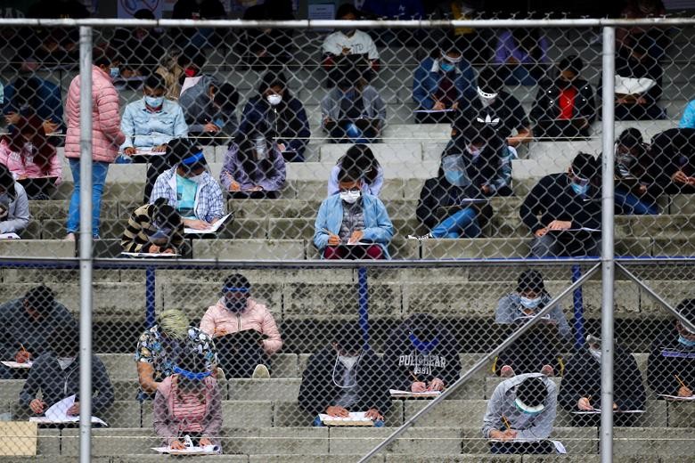 Young people wearing protective face masks maintain social distancing as they take the entrance exam for Mexico's National Autonomous University  in the stands of University Olympic Stadium in Mexico City. REUTERS/Edgard Garrido
